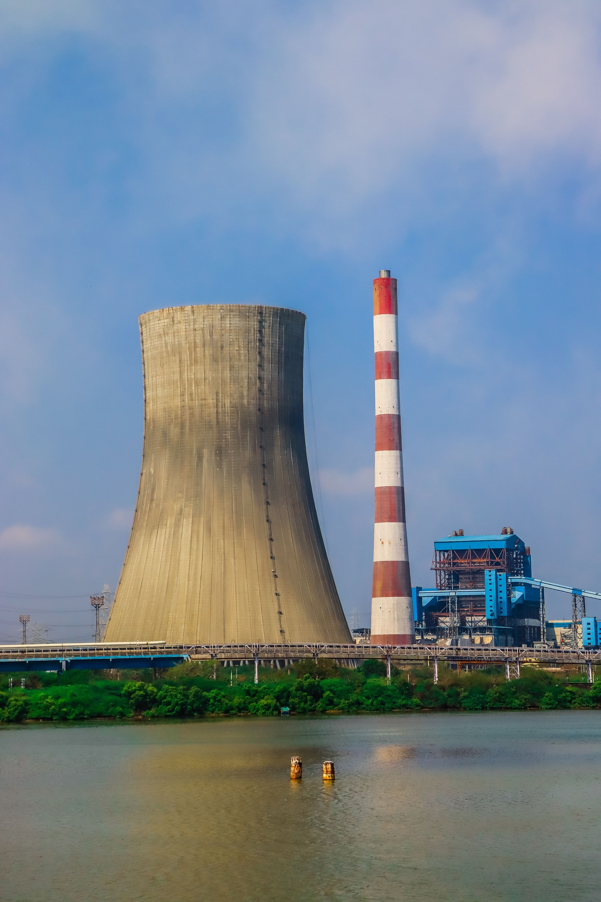 Active power plant cooling tower and striped stack beside water