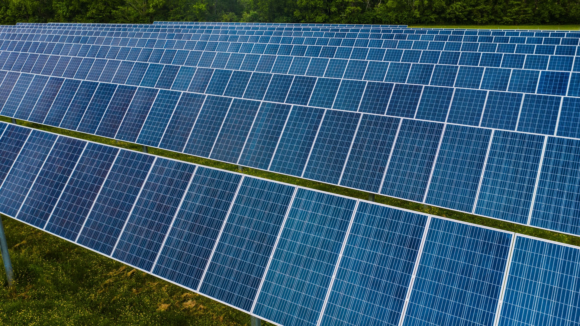 Aerial view of blue solar panel arrays over grassland
