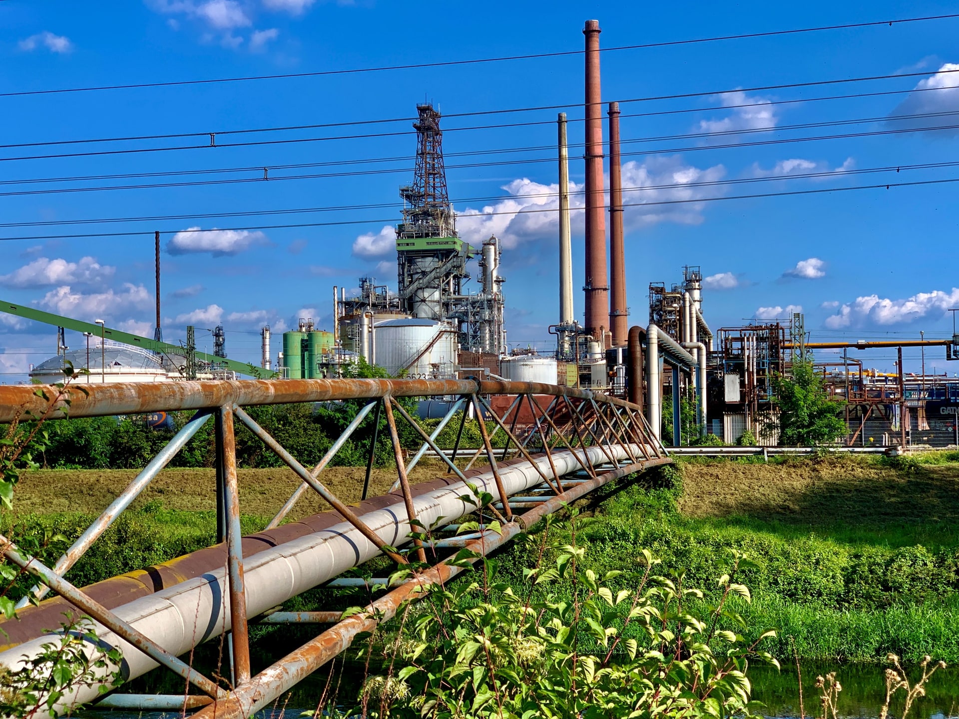 Pipeline bridge leading toward a large industrial energy complex